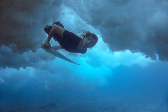 Underwater view of male surfer looking at camera while diving in ocean, Male, Maldives