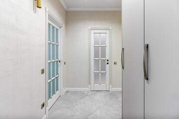 The interior of a stylish house in light colors with white doors with glass.