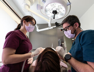 Dentist and and latin assistant examining a patient in dental clinic.
