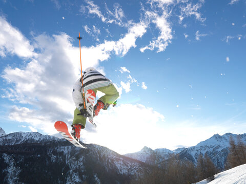 Low angle of airborne freestyle skier, mountains beyond