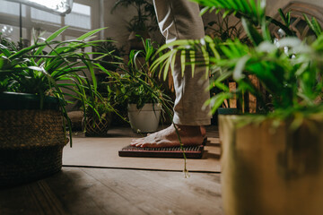 Man standing on wooden yogic board with metal nails