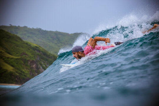 Surfer in Indian ocean near the coastline of Lombok island, Indonesia.