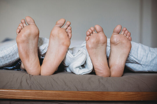 Detail of a couple's feets in bed in the morning