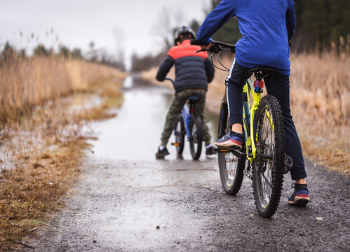 Cropped image of two boys on bikes going to ride through a puddle.