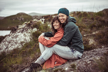 same sex female couple cuddle after hike in remote mountains