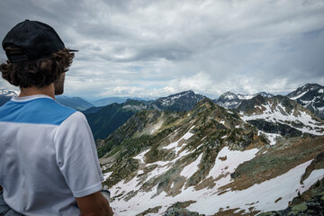 Young man stands, looking at mountain with a cloudy sky, BC, Canada