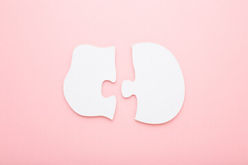 Different two white big puzzle pieces on light pink table background. Pastel color. Closeup. Baby simple jigsaw. Compatibility concept. Top down view.