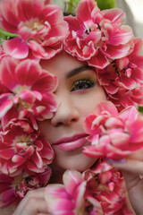 Portrait of a girl with good skin,perfume and cosmetics conceptThe face of beautiful woman with colorful make-up and flowers . The attractive woman lies in tulips.