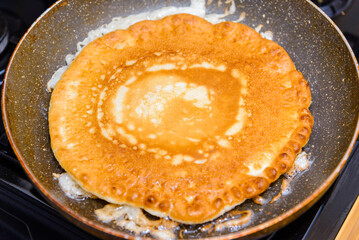 American Pancake burn on the pan,homemade pancake fried in a pan in the kitchen.Delicious thin pancake in frying pan on gas stove.Closeup.