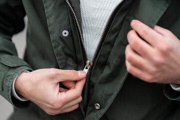 Close up view of a man unzipping his jacket.