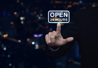 Businessman pressing open 24 hours flat icon over blur colorful night light city tower and...