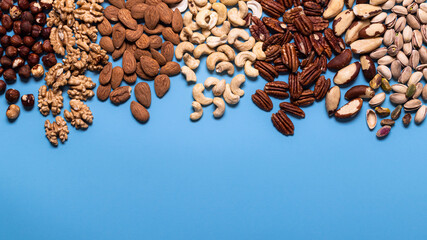 Top view, close-up, on a uniform blue background, a large variety of shelled dried fruit. Copy space