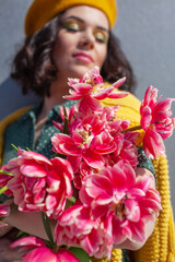 Portrait of a beautiful woman walks sround the city and holds a bouquet of pink flowers