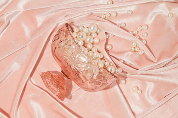 Romantic creative layout with crystal bowl and spilled pearls on pastel pink velvet background. 80s or 90s retro fashion aesthetic love concept. Minimal romantic idea.