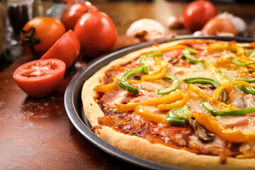 Homemade Italian pizza, mixed vegetables, cheese and bacon, fresh out of the oven. Placed on a dark wooden floor. Top view. Fast food concept.