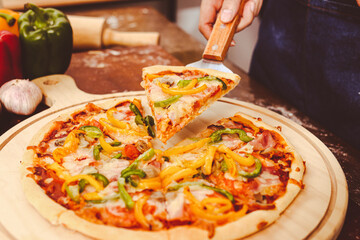 Homemade Italian pizza, mixed vegetables, cheese and bacon, fresh out of the oven. Placed on a dark wooden floor. Top view. Fast food concept.