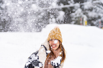 Fototapeta na wymiar Asian couple have fun playing snow during travel small town and forest mountain together on winter holiday vacation. Man and woman enjoy outdoor lifestyle travel local village in Japan in snowy day.