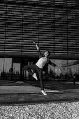 young attractive dancer in casual cloth doing ballet jump on the urban