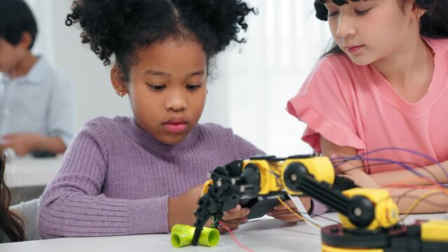 Elementary school students are sitting in the classroom at school and playing to robots class