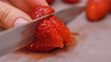 Women's hands cut strawberries with a knife