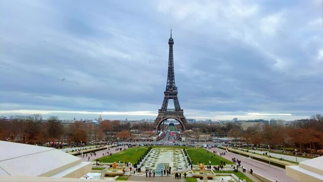 View of the Eiffel Tower in Paris from the Trocadero Square at cloudy weather, France. Gardens of the Trocadero with multiple people