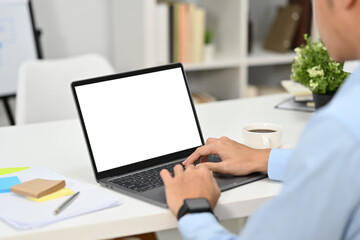 Fototapeta premium Closeup shot of male hands of businessman with smartwatch typing while working at laptop on white office desk