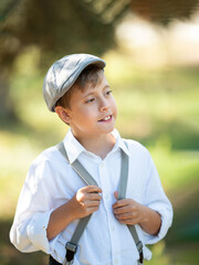 Funny happy child laughs, wears cap, suspenders, white t-shirt. Portrait kid boy in stylish retro clothes, outdoors. Summer spring day.