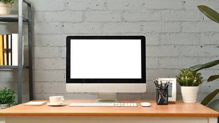 Comfortable workplace with computer and supplies against brick wall. Blank screen for graphic display montage
