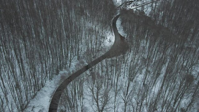 Aerial view of a serpentine road crossing a forest in wintertime with snow on Mount Terminio, Serino, Avellino, Irpinia, Campania, Italy.