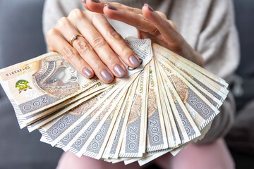 Kobieta trzyma w dłoniach banknoty, pieniądze polskie, złotówki. Liczenie pieniędzy.