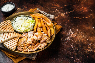 Turkish Doner kebab or gyros on a plate with french fries, vegetables and salad. Dark background. Top view. Copy space