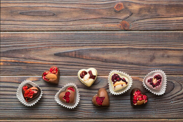 chocolate sweets in the form of a heart with fruits and nuts on a colored background. top view with space for text, holiday concept
