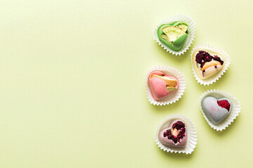 chocolate sweets in the form of a heart with fruits and nuts on a colored background. top view with space for text, holiday concept