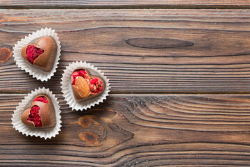 chocolate sweets in the form of a heart with fruits and nuts on a colored background. top view with space for text, holiday concept