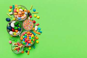 different colored round candy in bowl and jars. Top view of large variety sweets and candies with copy space