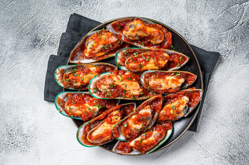 Large green mussels cooked in tomato sauce with garlic, parsley and lemon. White background. Top view