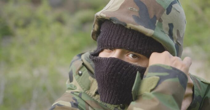 close up de sicario quitandose el casco encapuchado en la jungla