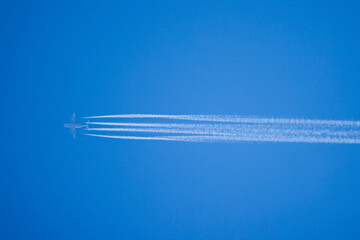 Airplane In Blue Sky With Plane Trails