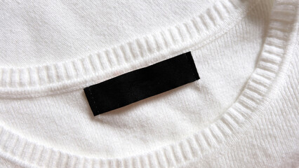 Black blank clothing tag label on new white shirt background