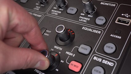 A sound engineer adjusts frequencies on a digital audio mixer. The man presses the buttons and...