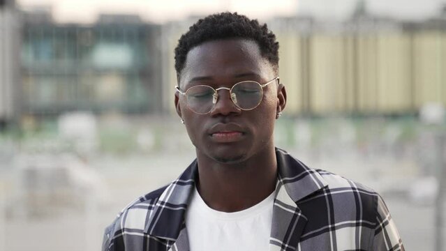Portrait serious African American man looking at camera in urban city - Confident guy wearing eyeglasses, human feelings 