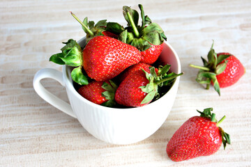 heap of fresh garden strawberries in white mug isolated on pastel background, macro