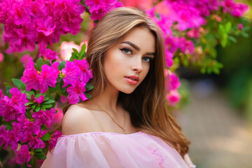 Close up portrait of Beautiful  girl in pink  vintage dress and straw hat standing in garden near colorful flowers. Art work of romantic woman .Pretty tenderness model looking at camera.