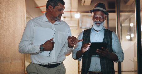 Partnership, tablet and businessmen walking in the office analyzing, talking and planning a project. Technology, professional and senior male employees working on a mobile device in the workplace.