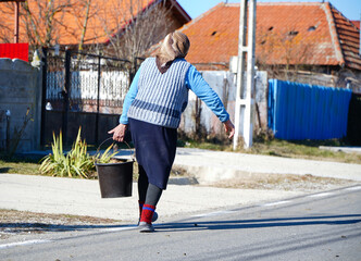 grandmother carrying a bucket of water in a rural area. the water crisis.