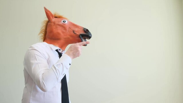 An office worker in a horse mask points his finger straight. Filming in the studio. 
