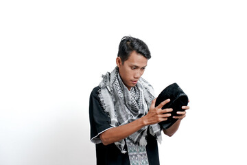 Religious Muslim Asian man wearing a turban, Muslim dress and preparing to wear a cap. Isolated on white background.