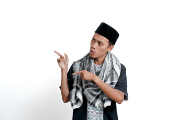 Religious muslim asian man wearing turban, muslim dress and cap, pointing to the side of empty space. Isolated on white background.