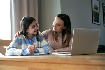 Caucasian mother with teenager daughter make homework at home