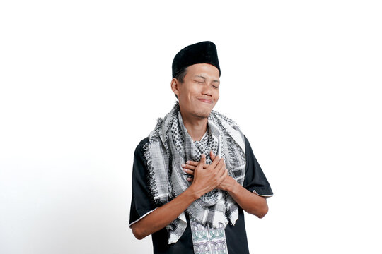 Religious muslim asian man wearing turban, muslim dress and cap. Smiling while holding the chest for calm. isolated on white background.
